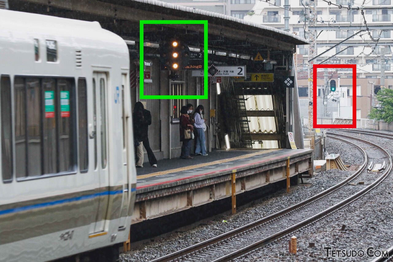 ランプが縦に並ぶ丸型の中継信号機（緑枠の部分）。右奥の信号機（赤枠の部分）が青であることを示しています