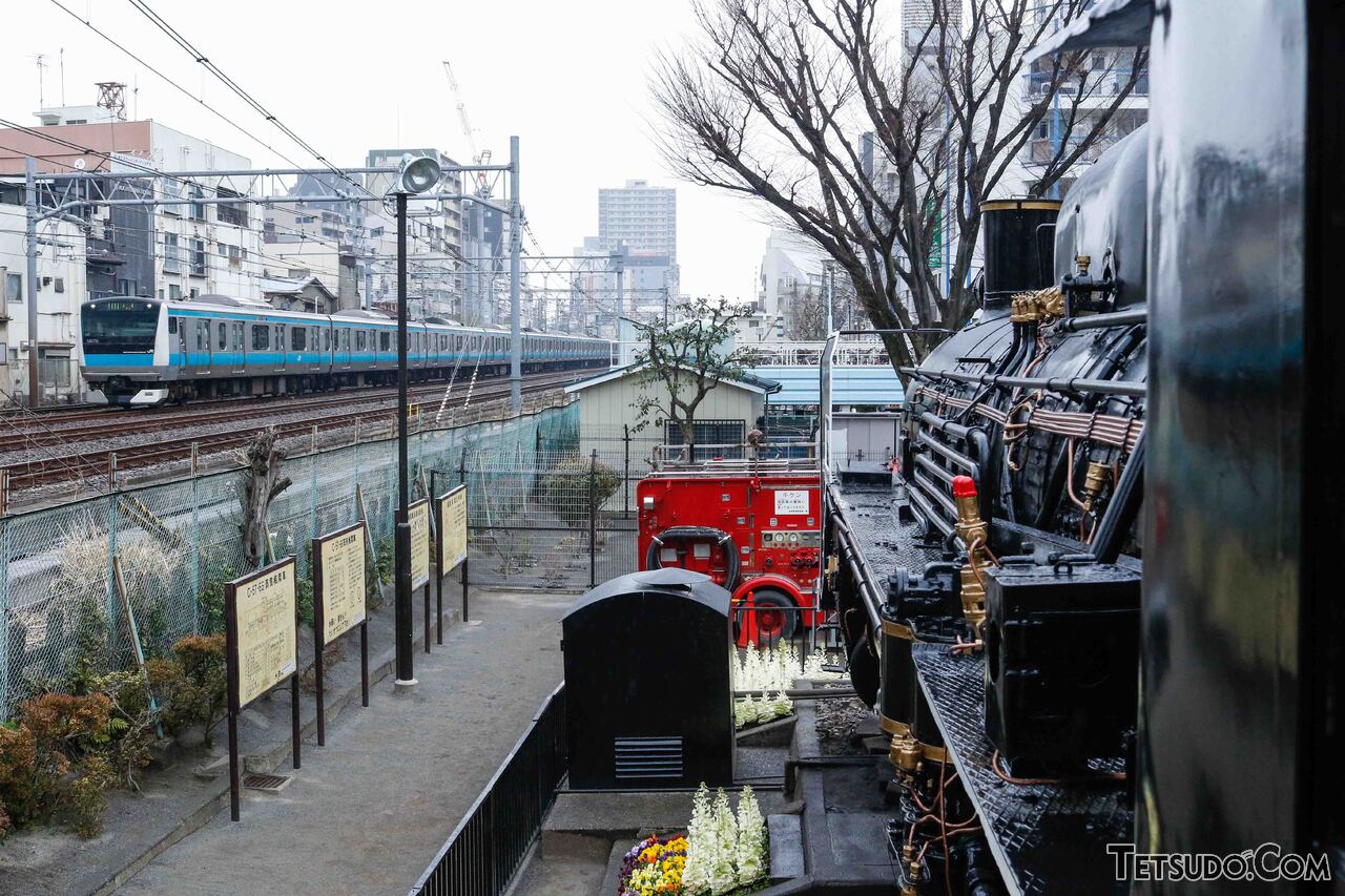 C57形66号機の脇を通過する京浜東北線。蒸気機関車と新型電車という、鉄道技術の進化を感じられる光景です