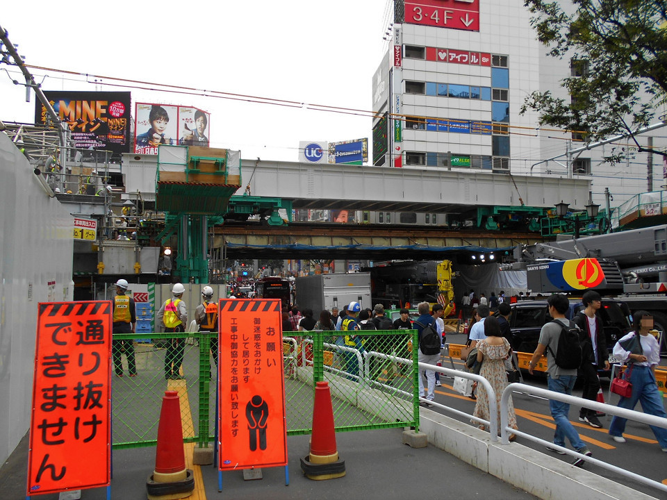 旧大山街道を行き交う人や車の様子。片側の車線には、大がかりな工事用車両が並び、その車列と仮の歩道との間に確保した車道を車がすれ違う状態になりました。写真奥側がスクランブル交差点(渋谷駅前交差点)です。